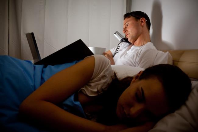 גבר צעיר עובד שעות נוספות גם מהמיטה